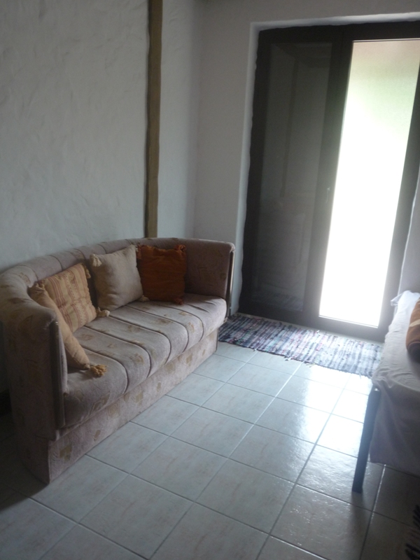 Wohnzimmer mit Sofa und Fliesenboden in einer Villa in Bigovo, Montenegro. Gemütliches Interieur mit Zugang zur Terrasse.