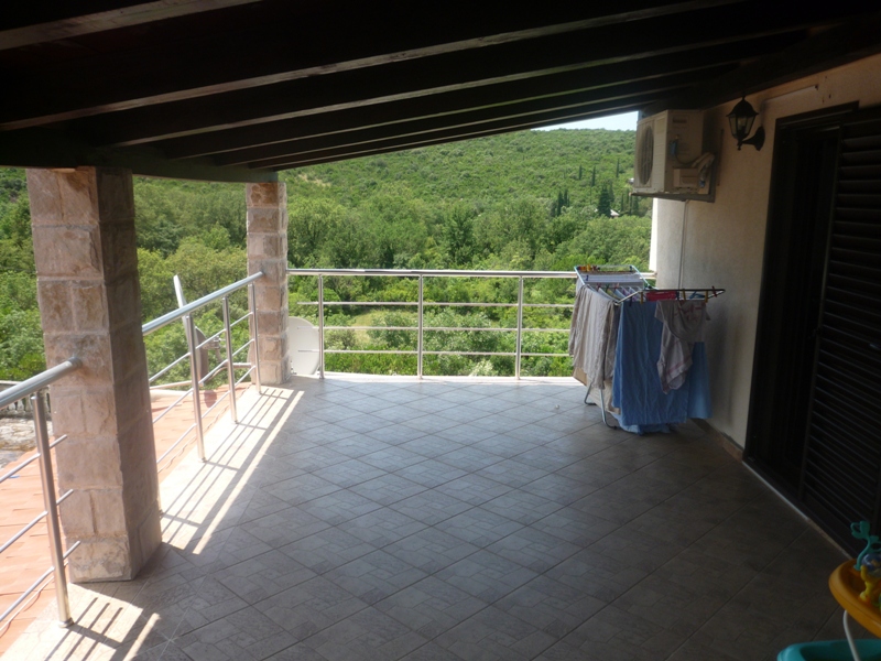 Geräumige Terrasse mit Steinsäulen und Blick auf grüne Hügel in der Villa Bigovo, Montenegro.