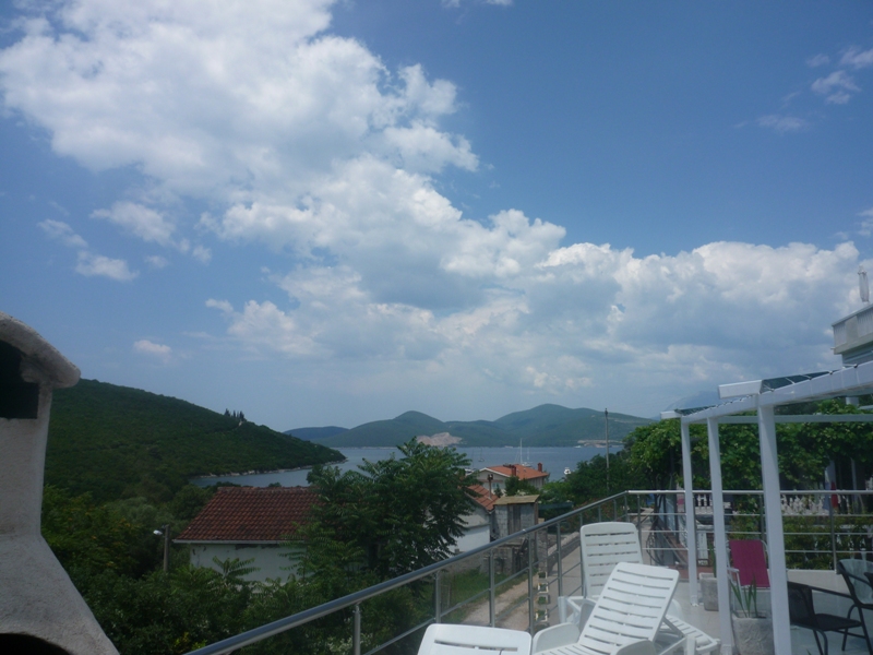 Blick von der Terrasse der Villa in Bigovo, Montenegro: weiße Liegestühle, Panoramablick auf das Meer, die Berge und die mediterrane Landschaft.