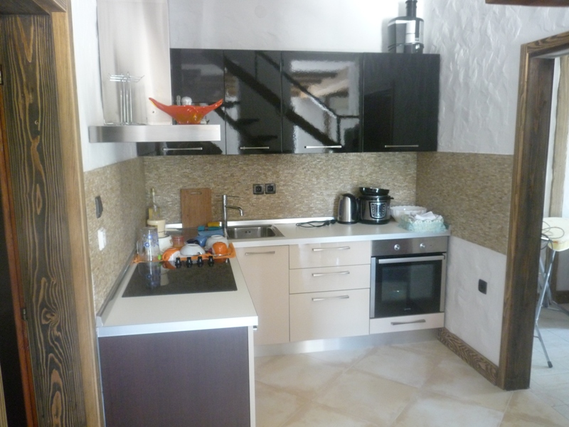 Moderne Küche in einer Villa in Bigovo, Montenegro: glänzende Fronten, Einbaugeräte und Steinrückwand.