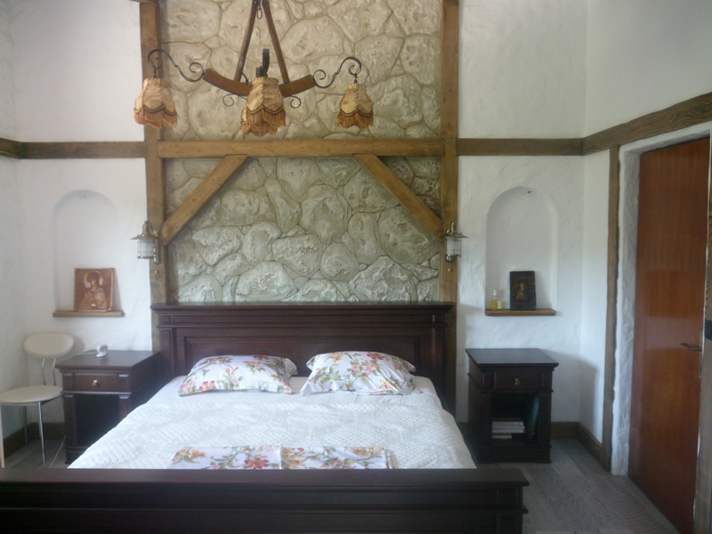 Schlafzimmer in einer Villa in Bigovo, Montenegro: Doppelbett, Stein- und Holzverkleidung, Wandnischen, stilvolles Interieur.