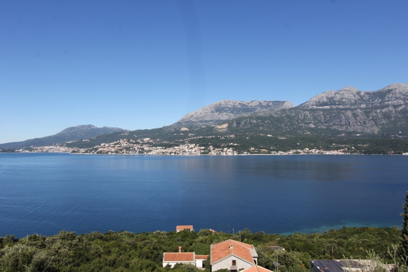 Panoramablick auf das Meer und die Berge vom Haus in Luštica, Montenegro: malerische Landschaft mit Küste und Ziegeldächern.