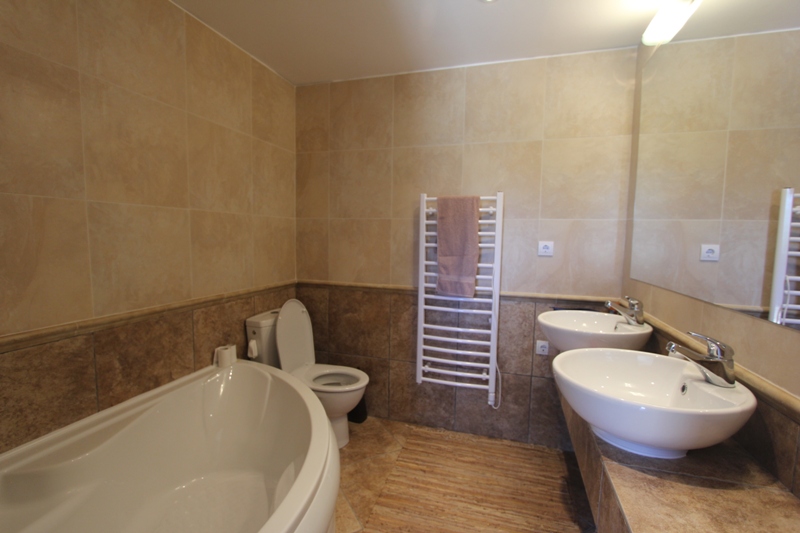Badezimmer mit zwei Waschbecken und Eckbadewanne im Haus, Luštica, Montenegro. Mit beigen Fliesen ausgestattet.