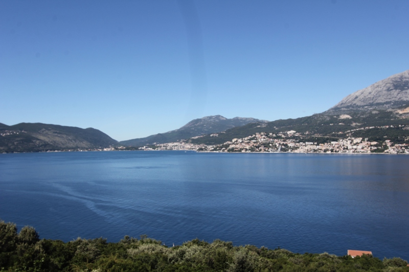Panoramablick auf das Meer und die Berge vom Haus in Luštica, Montenegro: malerische Bucht und Küstenstadt am Horizont.