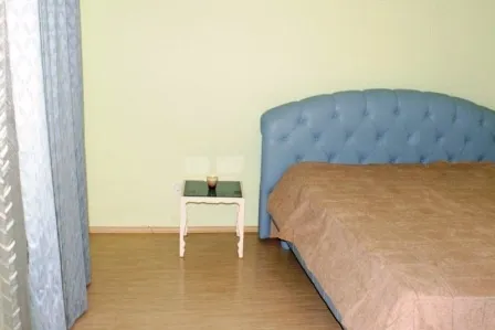 Schlafzimmer in einem Haus in Igalo, Montenegro: Doppelbett mit blauem gepolstertem Kopfteil und Nachttisch.