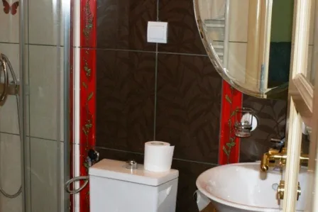Badezimmer in einem Haus in Igalo, Montenegro: Duschkabine, Waschbecken und Fliesenverkleidung mit roter Dekoration.