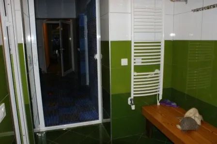 Badezimmer mit grünen Fliesen und einer Holzbank in einem Haus zum Verkauf in Igalo, Montenegro.