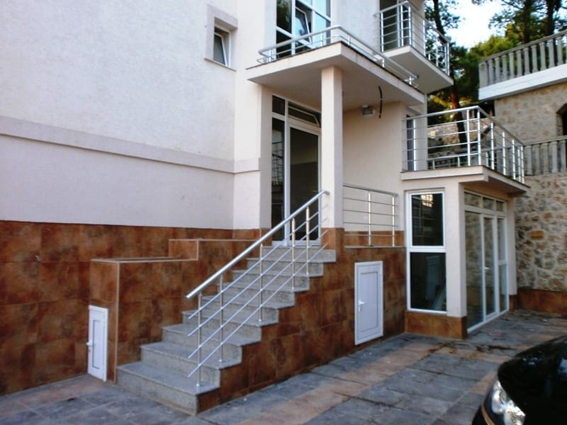 Entrance to a mini-hotel in Shushan, Montenegro: stone facade cladding, staircase with metal railings, and balconies.
