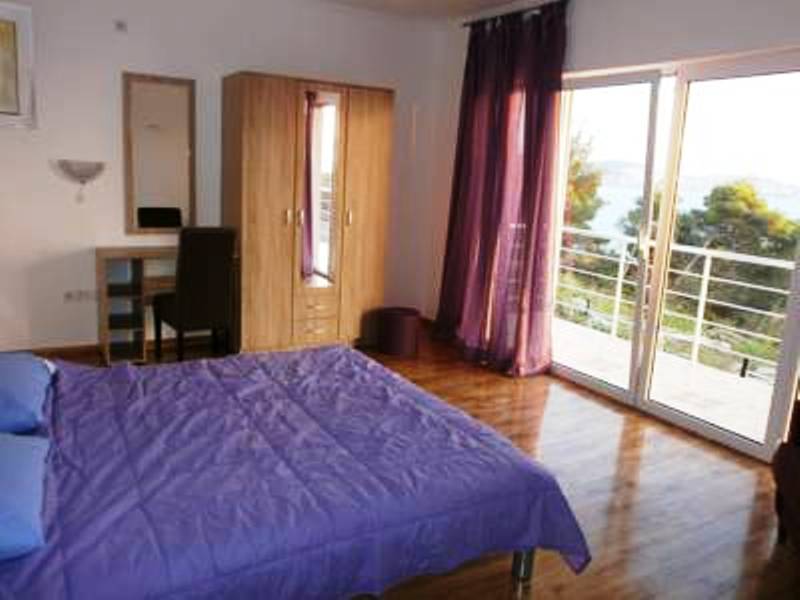 Bedroom in a hotel in Shushan, Montenegro: double bed, wooden wardrobe, dressing table, and sea view from the balcony.