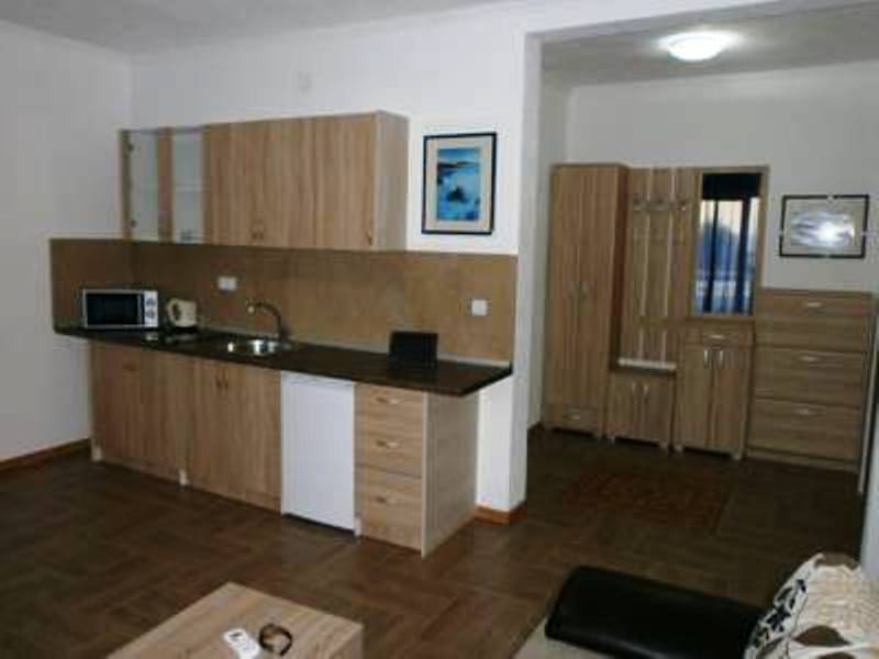 Kitchen in the Shushan mini-hotel, Montenegro: wooden cabinets, built-in appliances, and an entryway with wooden furniture.