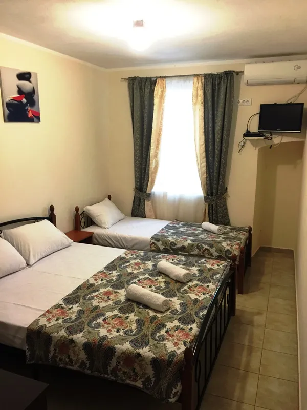 Schlafzimmer im Hotel in Đenovići, Montenegro: zwei Betten mit gemusterten Tagesdecken, Klimaanlage, TV und Fliesenboden.