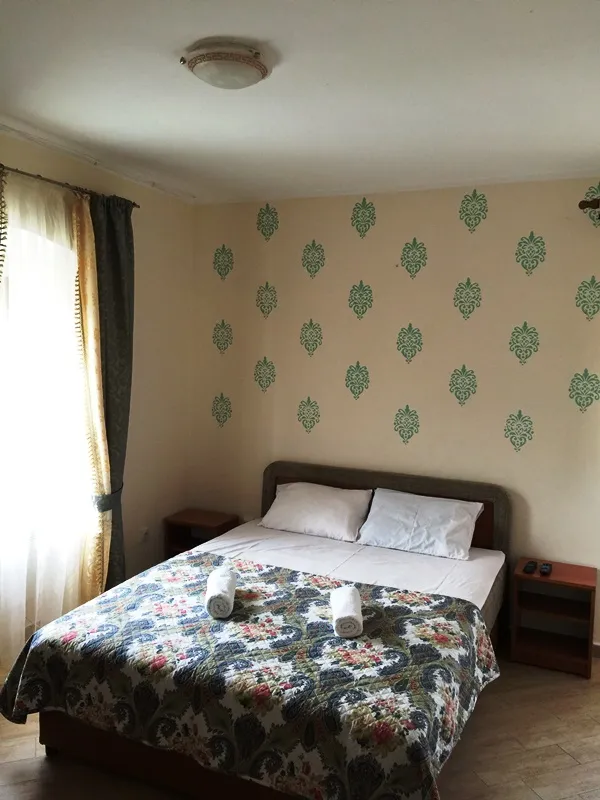 Gemütliches Schlafzimmer mit Doppelbett im Mini-Hotel Đenovići, Montenegro: helles Interieur, gemusterte Tapete.
