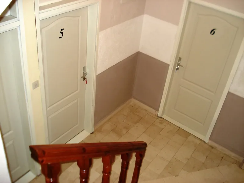Treppenabsatz mit den Türen der Zimmer 5 und 6 in einem Mini-Hotel, Đenovići, Montenegro: helle Wände und Fliesenboden.