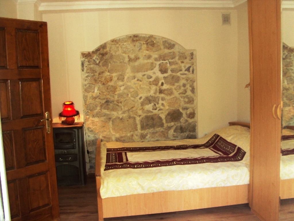 Schlafzimmer in einem Haus in Mišići, Bar, Montenegro: Bett, Kleiderschrank und Akzentwand aus Naturstein im Interieur.
