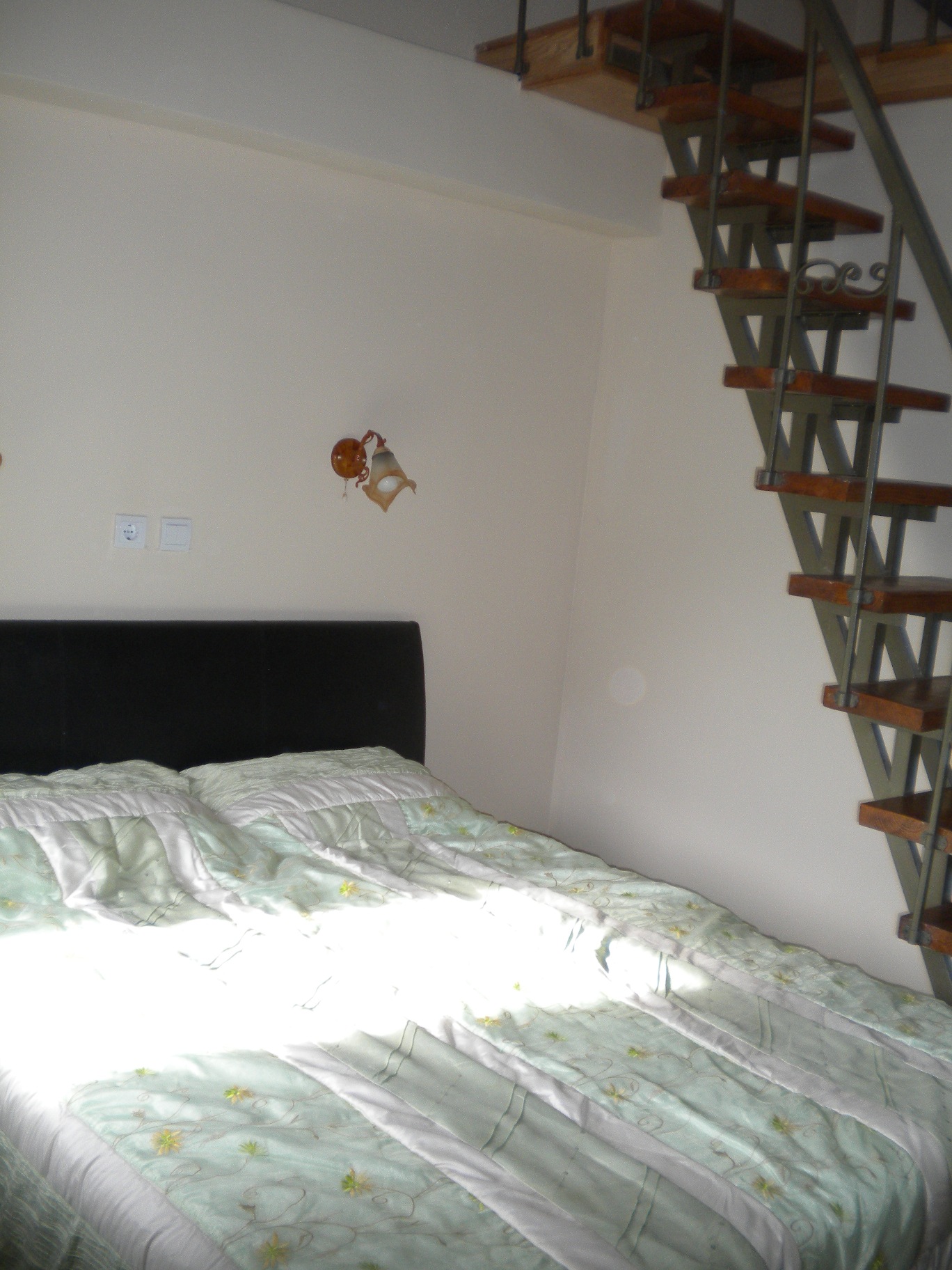 Schlafzimmer mit Doppelbett und Holztreppe ins Obergeschoss in einem Haus, Stadt Bar, Montenegro.