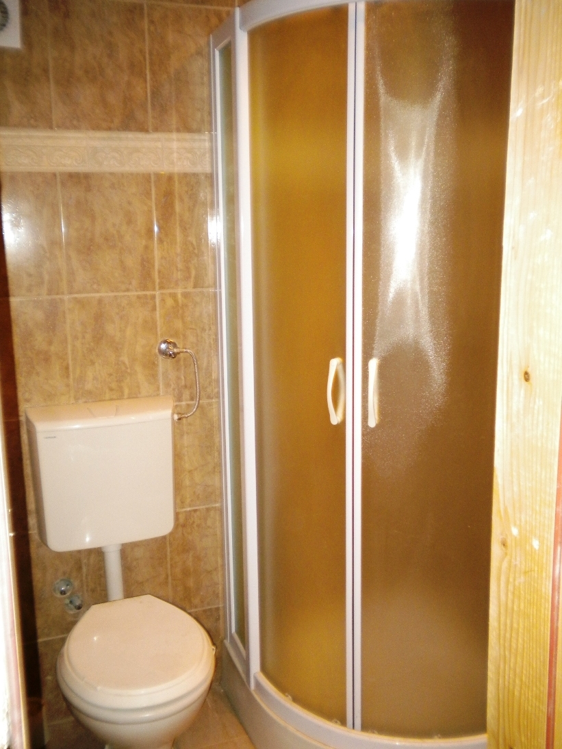 Badezimmer im Haus, Stadt Bar, Montenegro: Duschkabine mit matten Türen und weiße Sanitärkeramik, beige Fliesen.