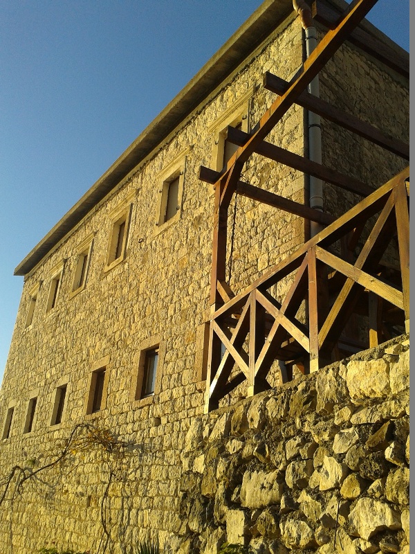 Fassade des Hauses aus Naturstein mit Holzterrasse im Dorf Mišići, Bar, Montenegro.