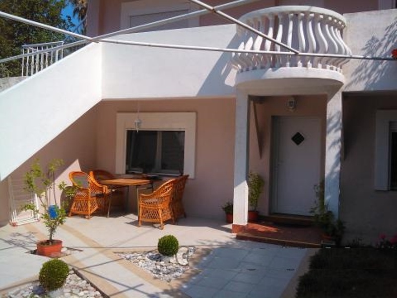 Terrasse des Hauses in Mišići, Bar, Montenegro: geflochtene Möbel, Steinverkleidung, Balkon mit Balustrade und gepflegter Hof.