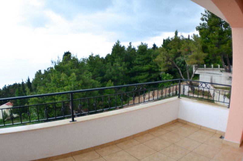 Offener Balkon mit schmiedeeisernem Geländer und Blick auf den Kiefernwald in einem Haus, Stadt Shushan, Montenegro.