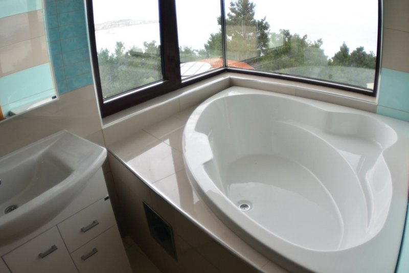 Badezimmer mit Eckbadewanne und Panoramablick auf das Meer in einem Haus, Šušanj, Montenegro.