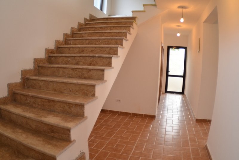 Treppe mit Steinverkleidung in einem Haus in Šušanj, Montenegro: heller Innenraum mit Fliesenboden und Ausgang nach draußen.