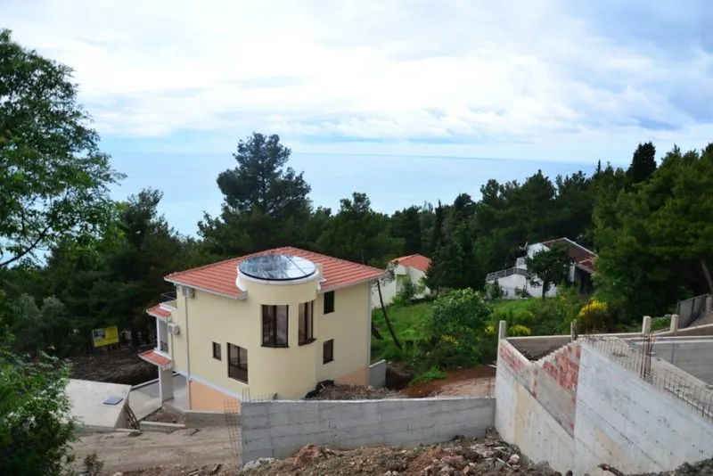 Zweistöckiges Haus mit Panoramafenster und Meerblick im Ort Šušanj, Montenegro, vor dem Hintergrund eines Kiefernwaldes.