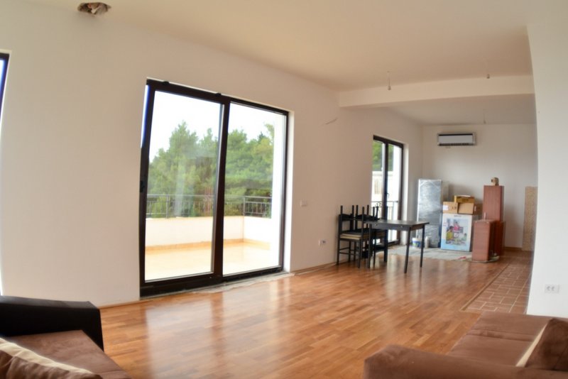 Helles Wohnzimmer in einem Haus in Šušanj, Montenegro: Panoramafenster, Zugang zur Terrasse, Parkettboden und Möbel.