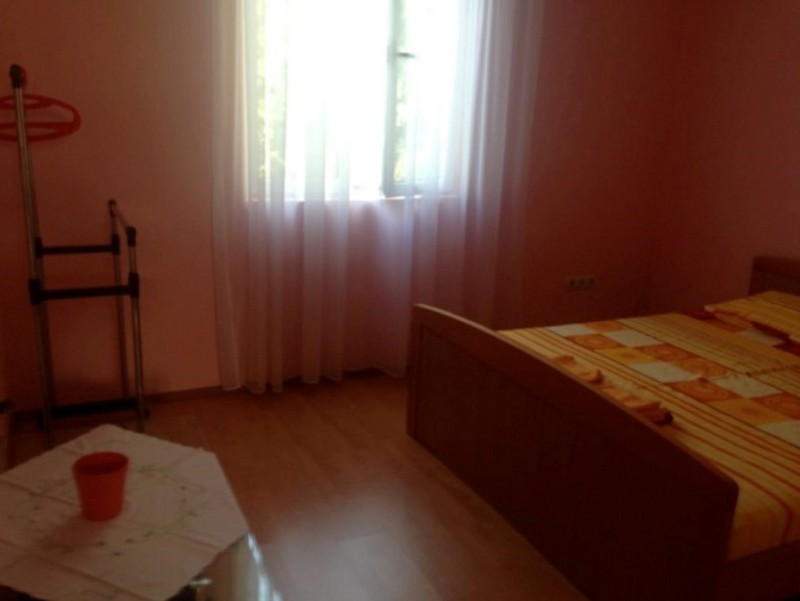 Schlafzimmer mit einem Bett, einem Fenster mit Vorhängen und einem Herrendiener.