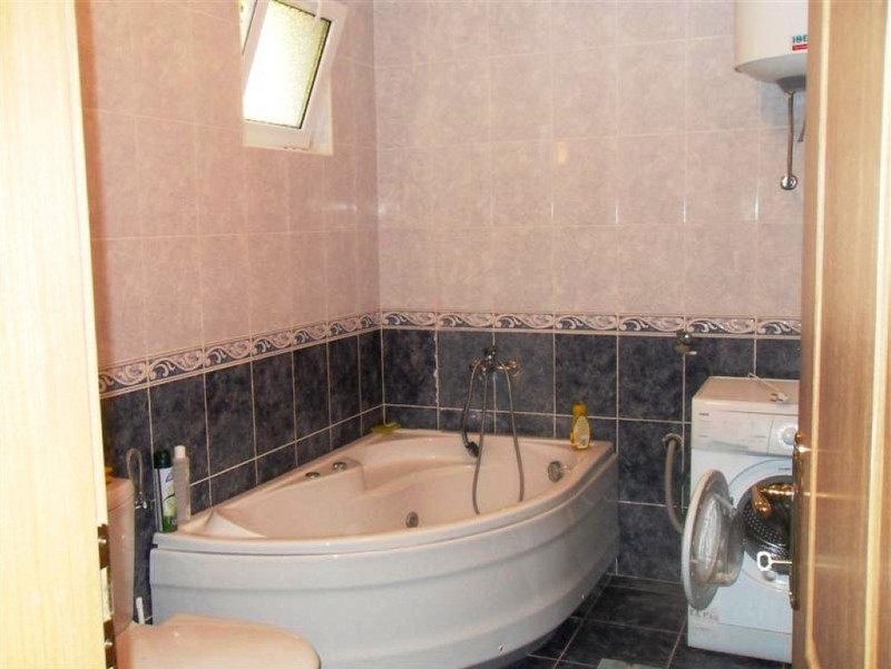 Ein kompaktes Badezimmer mit Eckbadewanne, Toilette und Waschmaschine.