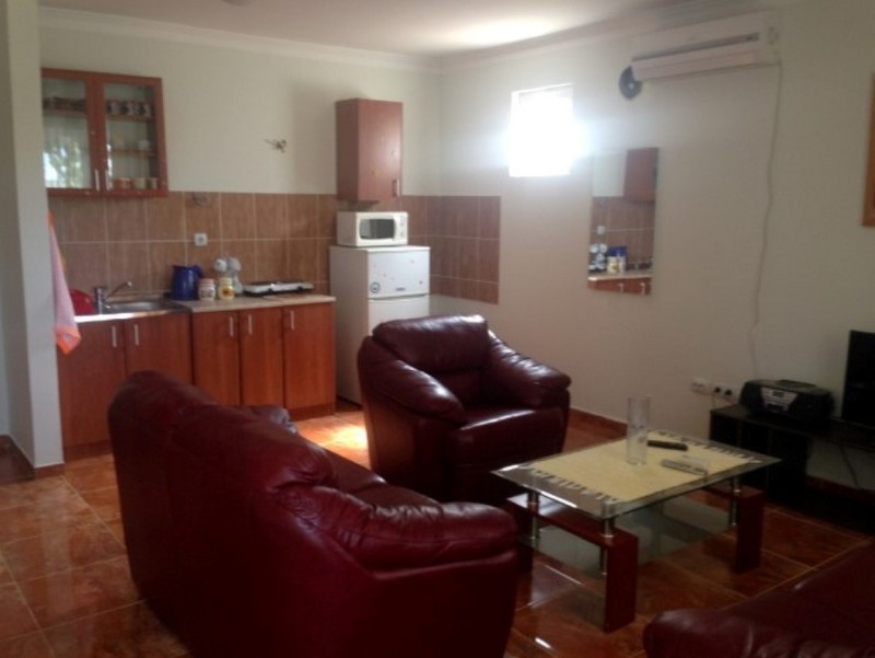 Ein Wohnzimmer mit rotem Sofa, Sessel, Couchtisch und offenem Küchenbereich.