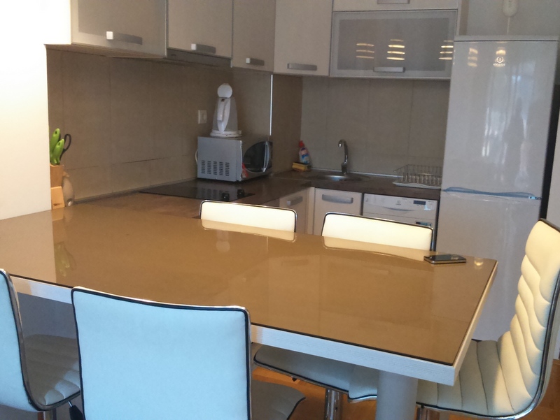 Eine moderne Küche mit Esstisch, Stühlen, Kühlschrank und Schränken.