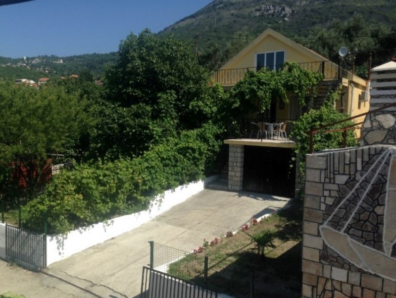 Außenansicht eines zweistöckigen gelben Hauses mit Balkon, Garage und Hof