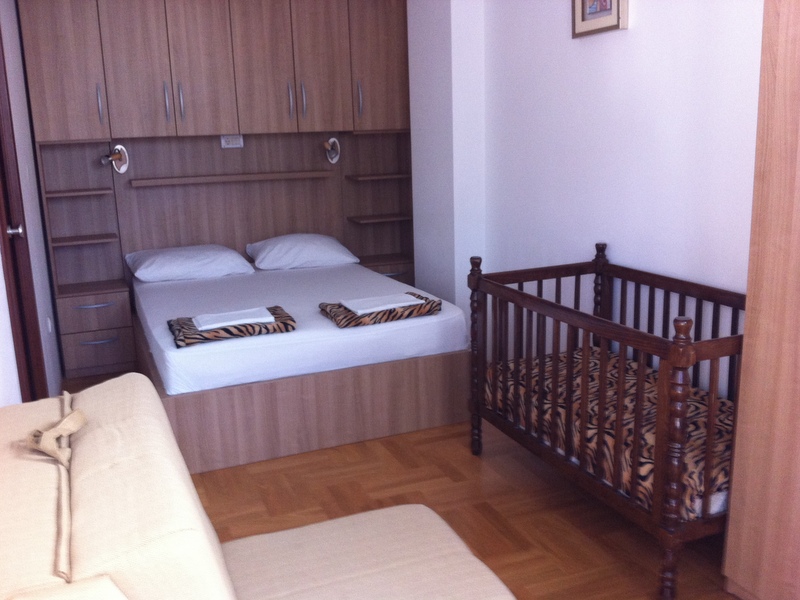 Schlafzimmer mit Doppelbett, Wandschrank und Babybett.
