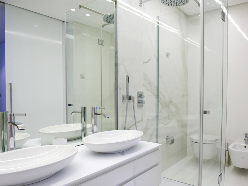 Dukley, Bečići, Karadağ’daki dairelerde mermer görünümlü kaplamaya sahip modern banyo: iki lavabo ve duş.