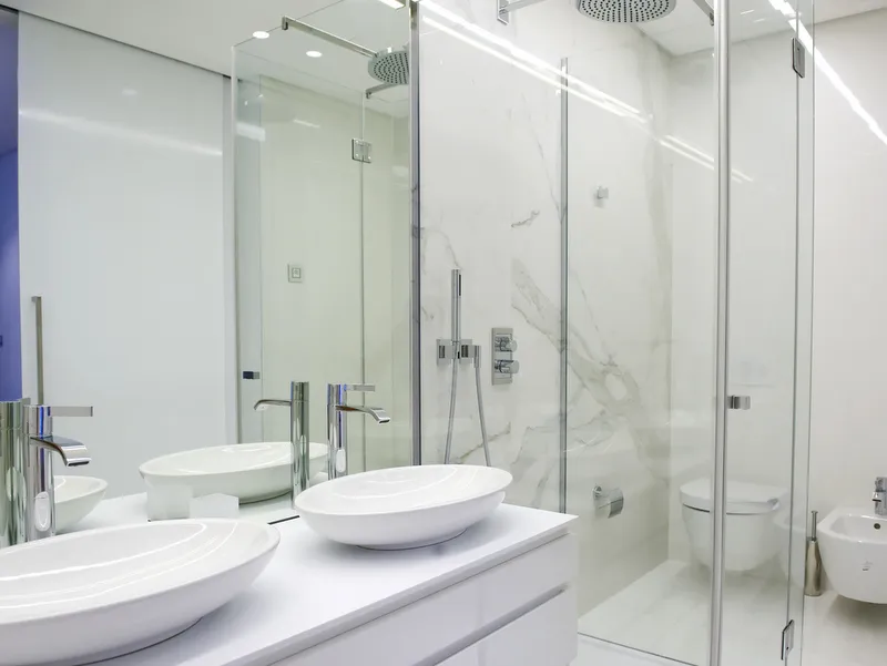 Modernes weißes Badezimmer mit zwei Aufsatzwaschbecken und Glasdusche.