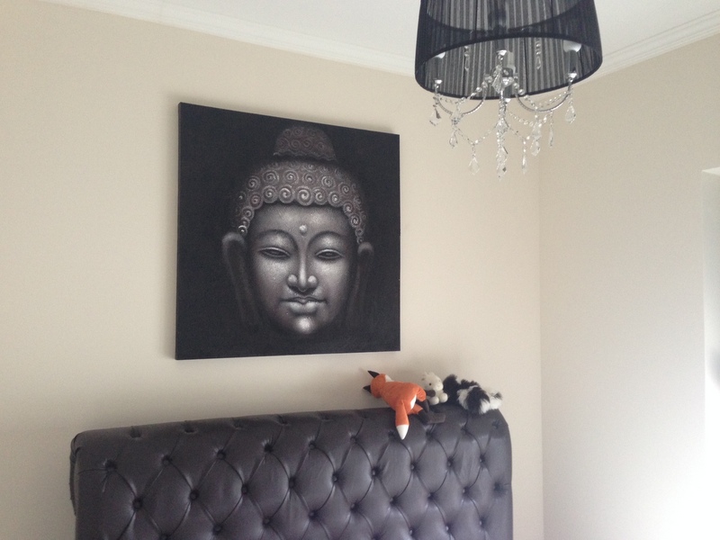 Schlafzimmerinterieur in einer Wohnung in Dobrota, Montenegro: Leder-Kopfteil des Bettes, ein Buddha-Gemälde und ein schwarzer Kronleuchter.