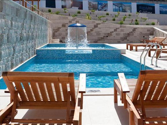 Offener Pool mit Springbrunnen und Holzliegen in der Wohnanlage, Dobrota, Montenegro.