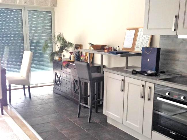 Küche in einer Wohnung in Dobrota, Montenegro: moderne Einbauküche, Bartheke, dunkle Fliesen und Panoramafenster.