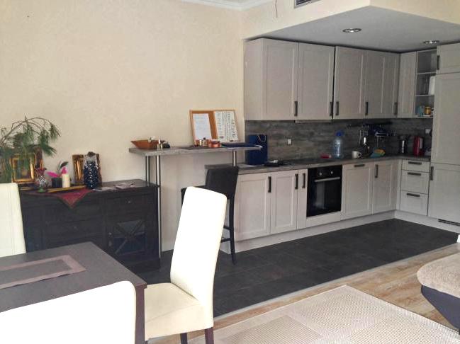 Moderne Küche in einer Wohnung in Dobrota, Montenegro: helle Einbauküche, Bartheke und Essbereich mit Möbeln.