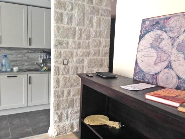 Innenraum einer Wohnung in Dobrota, Montenegro: Küche mit hellen Fronten und Akzentwand aus Naturstein.