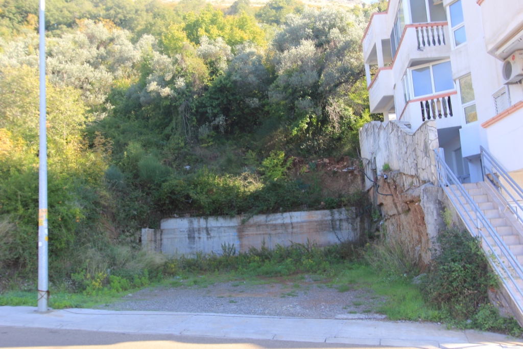 Baugrundstück neben einem Wohnhaus in Petrovac, Montenegro: Blick auf das Grundstück und die Stützmauer.