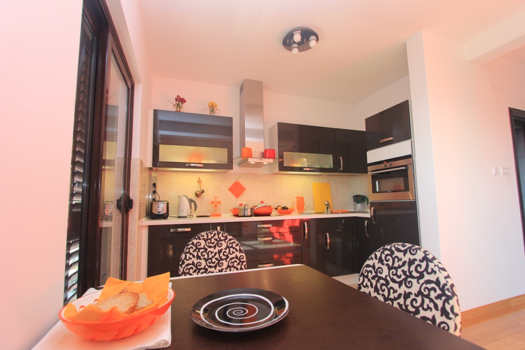 Moderne Küche mit dunkler Einbauküche und Essbereich in einer Wohnung in Rafailovići, Montenegro.