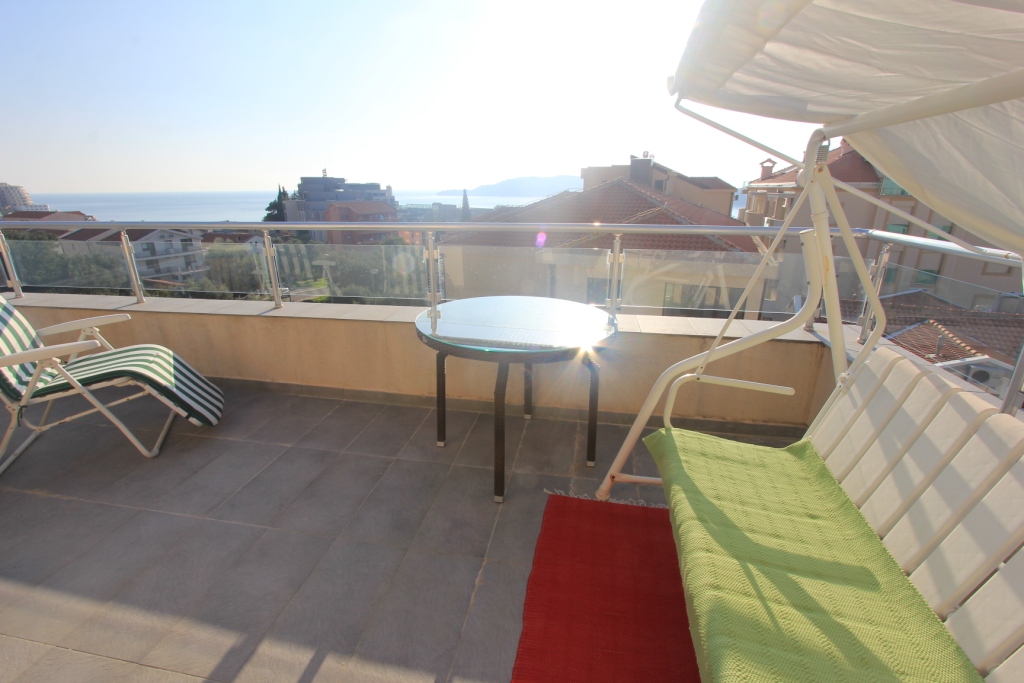 Geräumiger Balkon mit Möbeln und Meerblick in einer Wohnung in Rafailovici, Montenegro: Schaukel, Tisch und Liegestuhl.