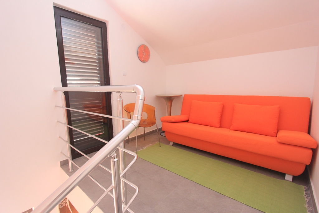 Wohnzimmer mit orangefarbenem Sofa in einer Wohnung in Rafailovići, Montenegro: modernes Interieur und Zugang zum Balkon.