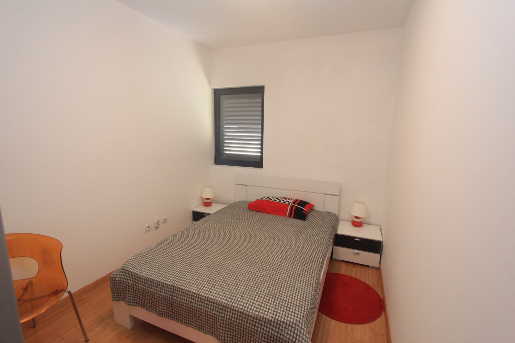 Helles Schlafzimmer mit Doppelbett in einer Wohnung, Rafailovići, Montenegro: moderne Möbel und ein Fenster mit Jalousien.