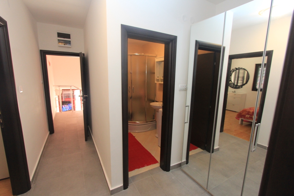 Flur in einer Wohnung in Rafailovici, Montenegro: eingebauter Spiegelschrank, helle Ausstattung und Eingang zum Badezimmer.