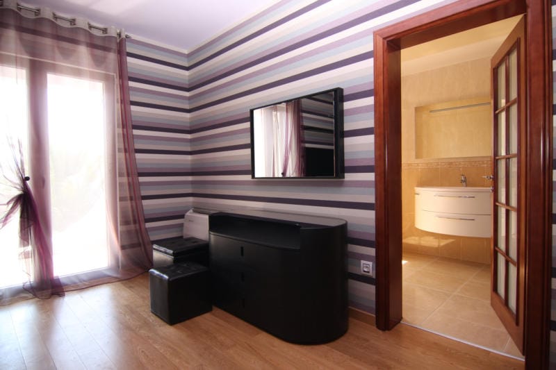 Chambre avec papier peint rayé, mobilier noir et accès à la salle de bains dans une villa à Lastva, Monténégro.