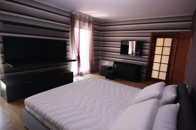 Chambre moderne avec lit double et papier peint rayé dans une villa à Lastva, Monténégro.