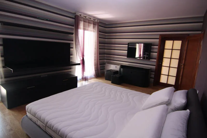 Chambre moderne avec lit double et papier peint rayé dans une villa à Lastva, Monténégro.