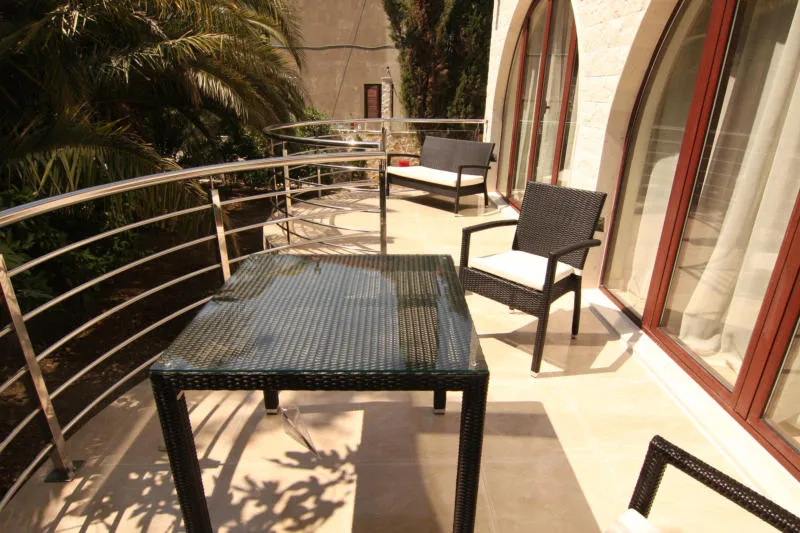 Spacieuse terrasse de la villa à Lastva, Monténégro : mobilier en osier, table en verre et garde-corps en acier inoxydable.